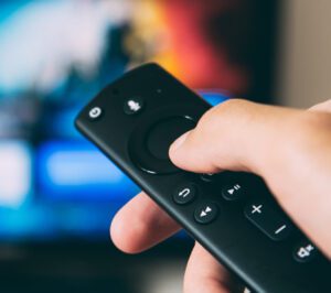 blurred TV screen with hand aiming an in-focus remote